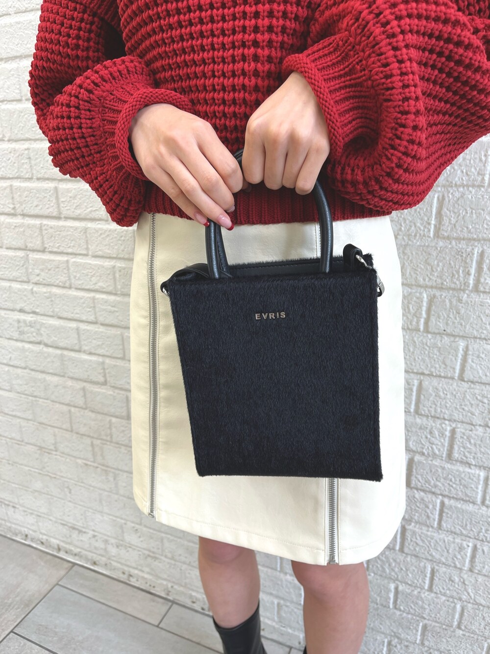 ブラック系のブーツ、ホワイト系のダウンジャケット/コート、ブラック系のショルダーバッグを着用したレディースの冬コーディネートの3枚目の写真