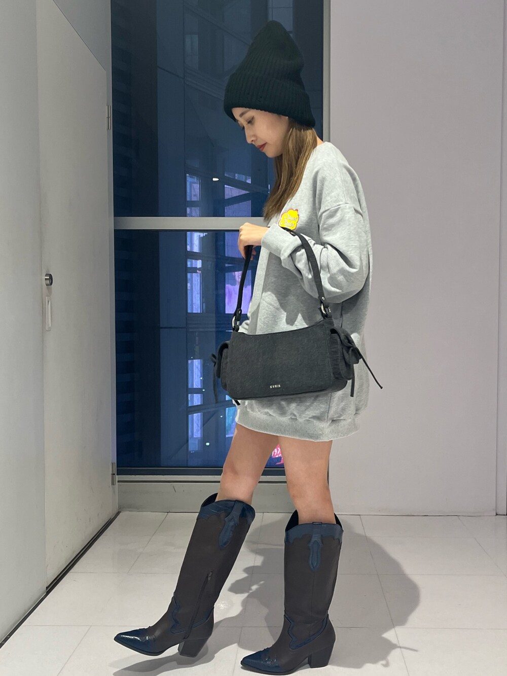 ブラック系のハンドバッグ、グレー系のTシャツ/カットソー、ブラウン系のブーツを着用したレディースの秋コーディネートの2枚目の写真