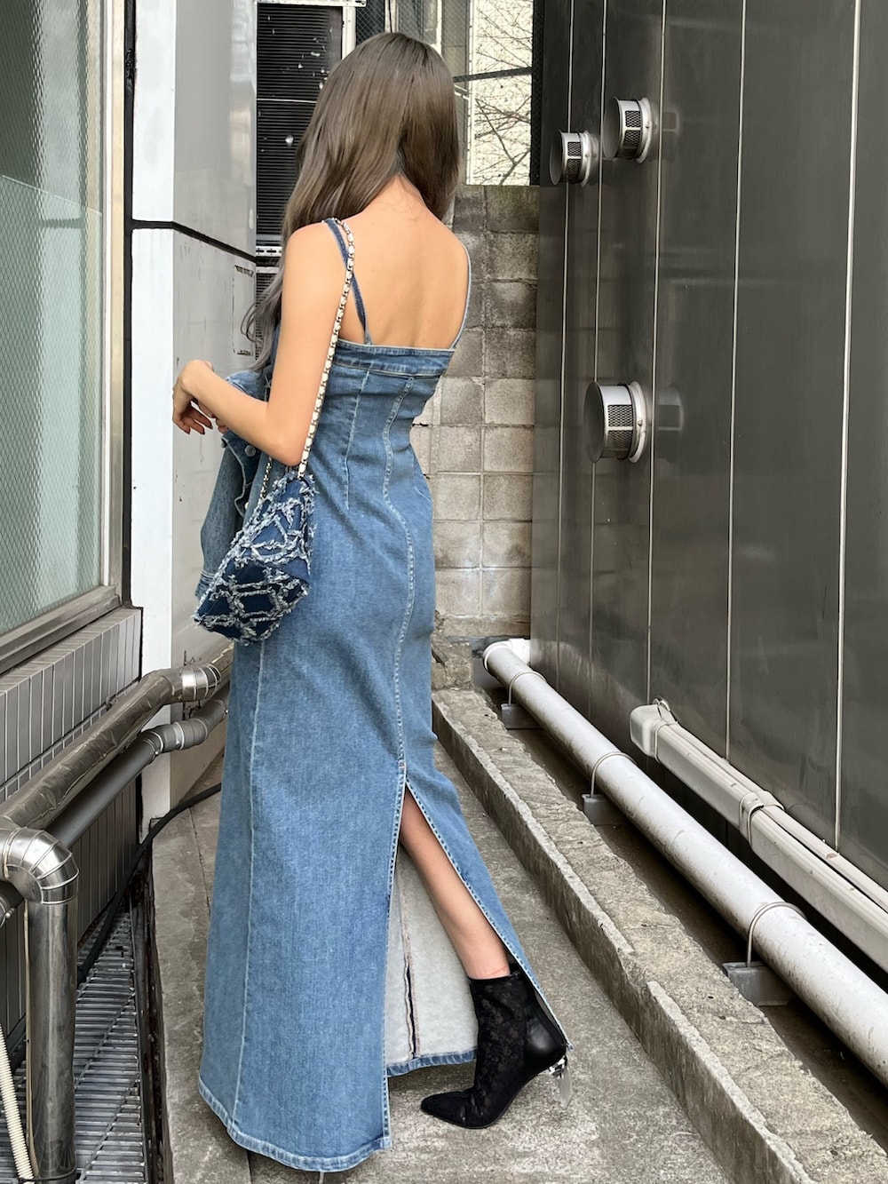 ブルー系のデニムジャケット、ブルー系のワンピース、ブルー系のショルダーバッグを着用したレディースの冬コーディネートの4枚目の写真