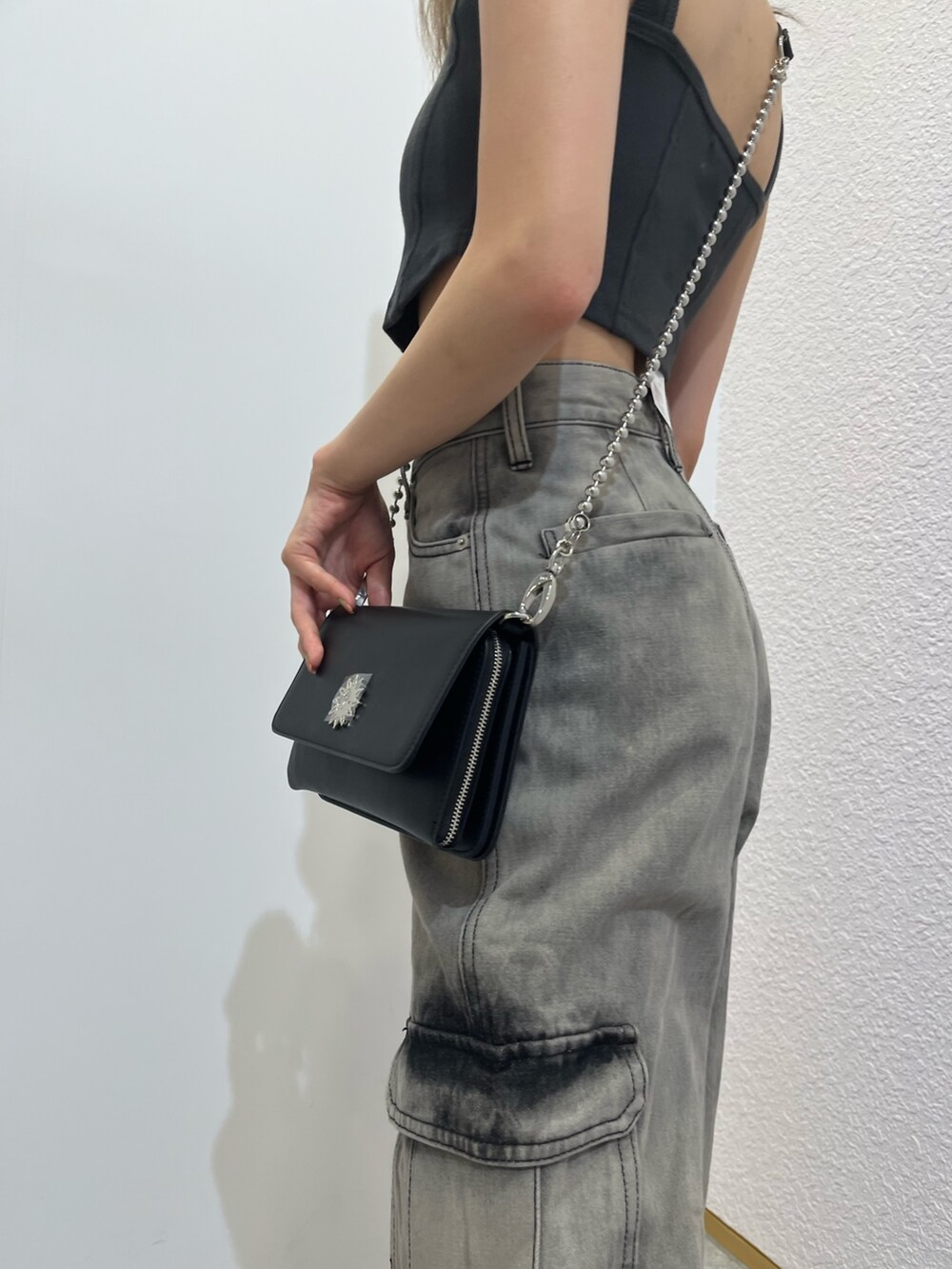 シルバー系のショルダーバッグ、ブラック系のキャミソール、ブラック系のデニムパンツを着用したレディースの夏コーディネートの6枚目の写真