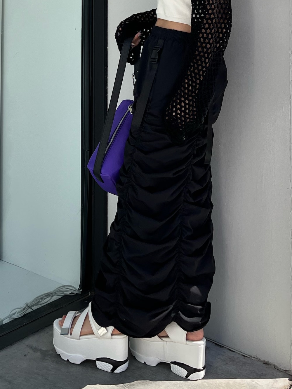 ブラック系のスカート、ブラック系のニット/セーター、パープル系のハンドバッグを着用したレディースの春コーディネートの6枚目の写真