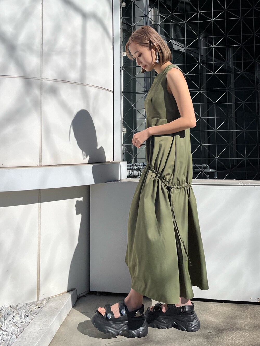 グリーン系のワンピース、ホワイト系のサンダルを着用したレディースの春コーディネートの2枚目の写真