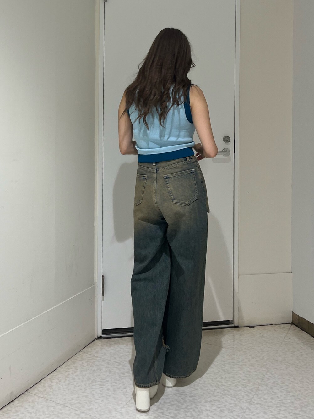 ブラック系のハンドバッグ、ブルー系のデニムパンツ、ブルー系のニット/セーターを着用したレディースの夏コーディネートの3枚目の写真