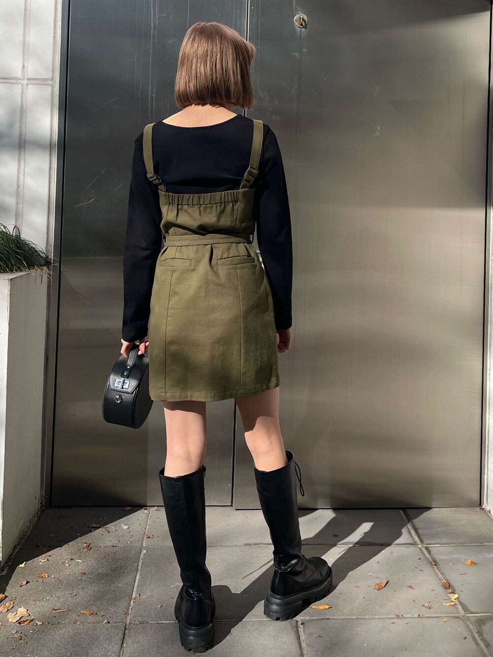 ブラック系のワンピース、ブラック系のショルダーバッグ、ブラック系のブーツを着用したレディースの冬コーディネートの3枚目の写真