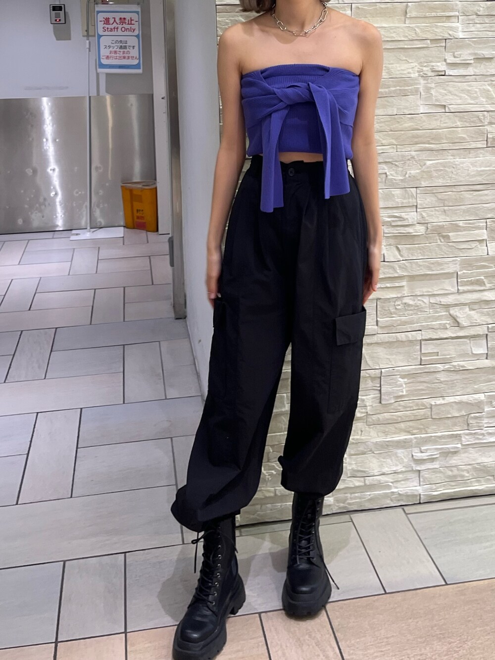 オレンジ系のカーゴパンツ、ブラック系のブーツ、パープル系のチューブトップを着用したレディースの春コーディネートの2枚目の写真
