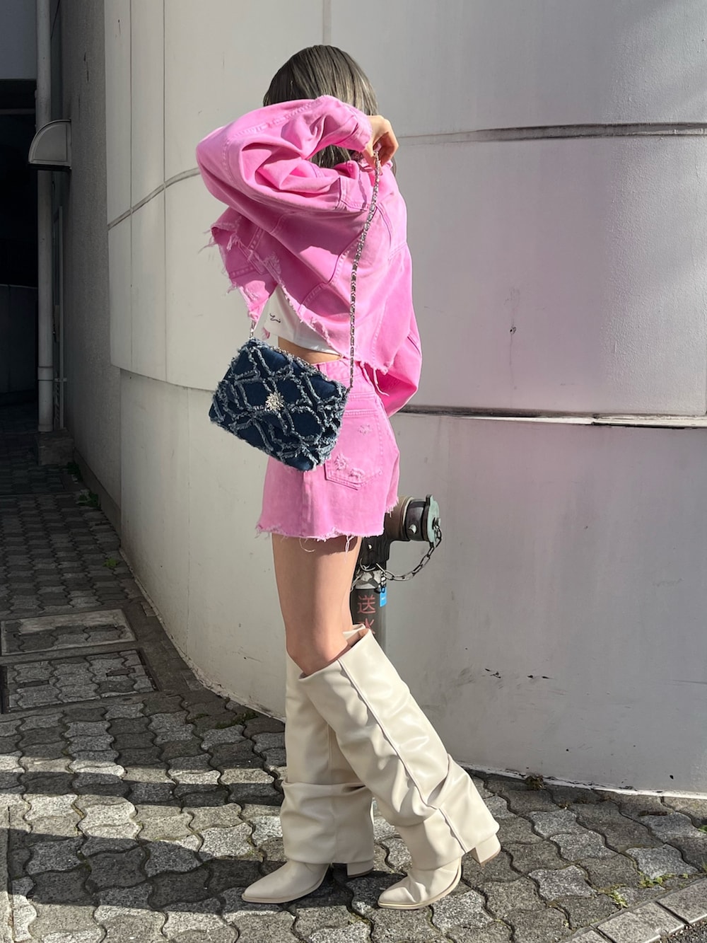 ピンク系のデニムジャケット、ピンク系のデニムパンツ、ホワイト系のブーツを着用したレディースの冬コーディネートの2枚目の写真