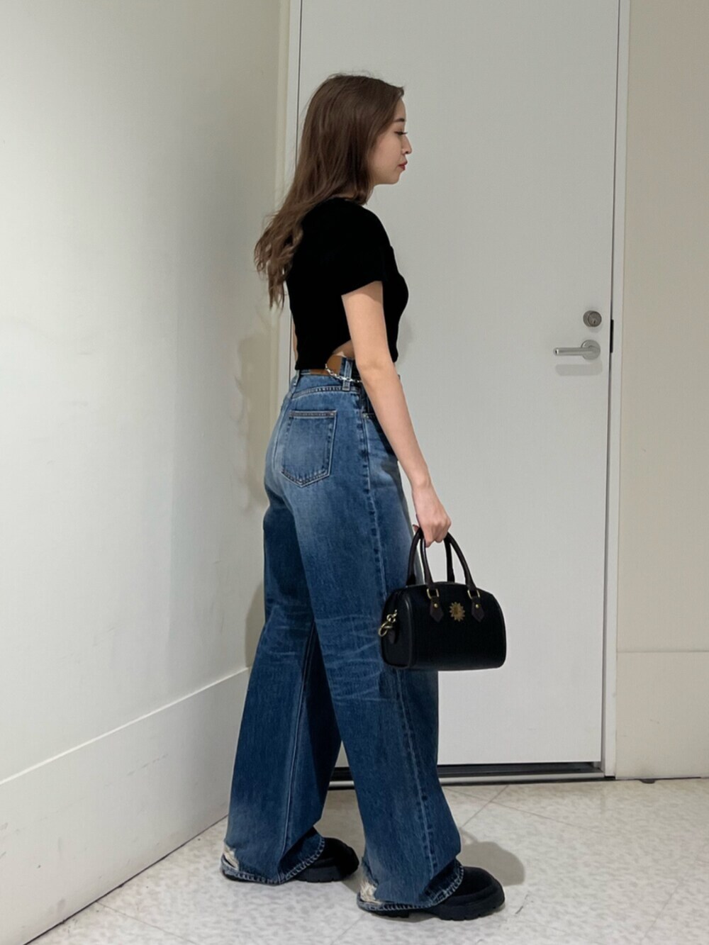 ブラック系のブーツ、ブルー系のデニムパンツ、その他のショルダーバッグを着用したレディースの春コーディネートの4枚目の写真