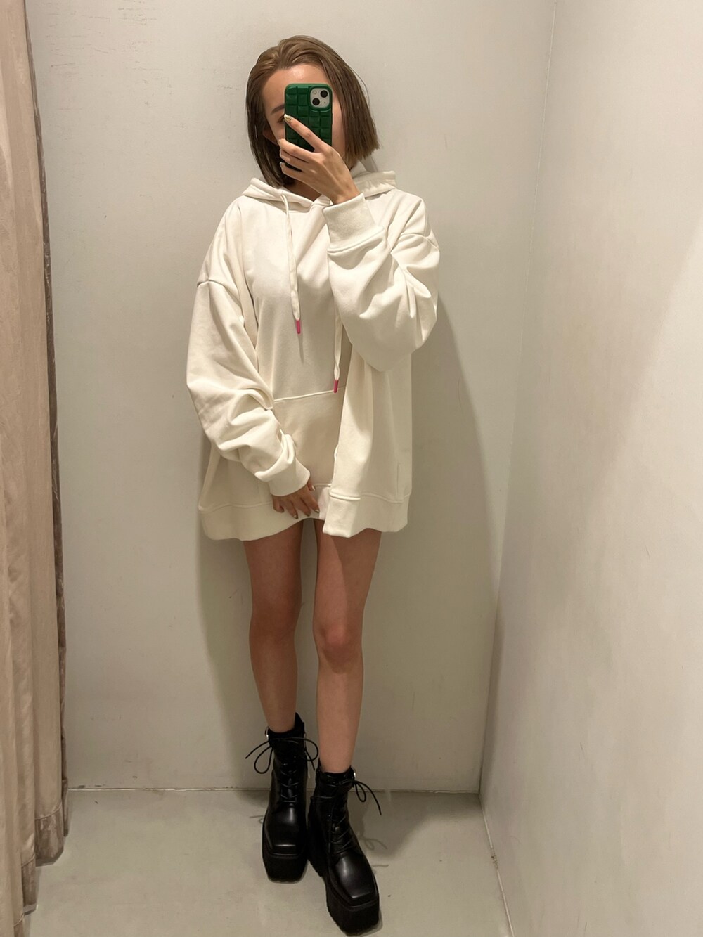 ホワイト系のパーカー、パープル系のスタジャン、ブラック系のブーツを着用したレディースの冬コーディネートの5枚目の写真