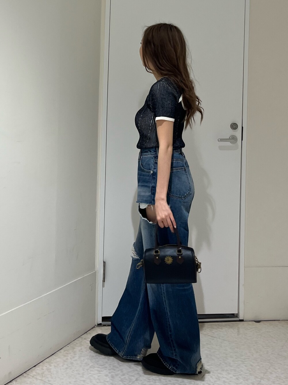 ブラック系のニット/セーター、ブルー系のデニムパンツ、その他のショルダーバッグを着用したレディースの春コーディネートの2枚目の写真