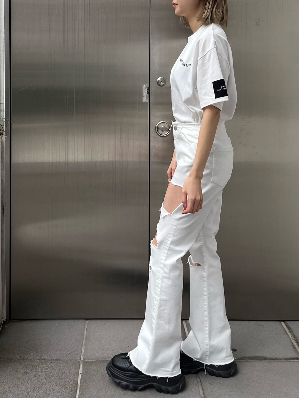 ホワイト系のデニムパンツ、ホワイト系のTシャツ/カットソー、ブラック系のスニーカーを着用したレディースの春コーディネートの2枚目の写真