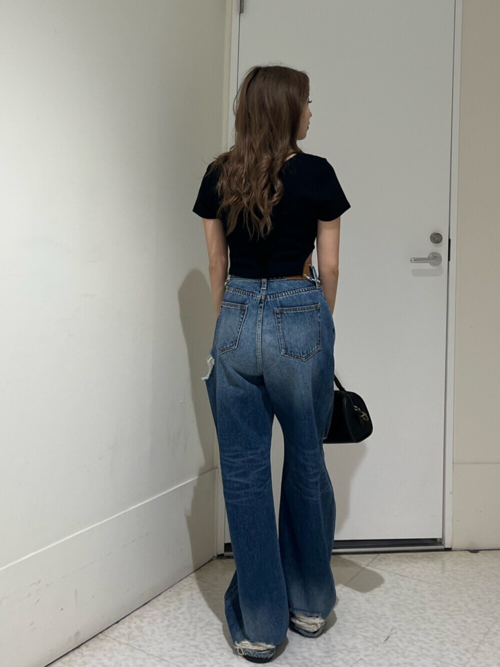 ブラック系のブーツ、ブルー系のデニムパンツ、その他のショルダーバッグを着用したレディースの春コーディネートの3枚目の写真