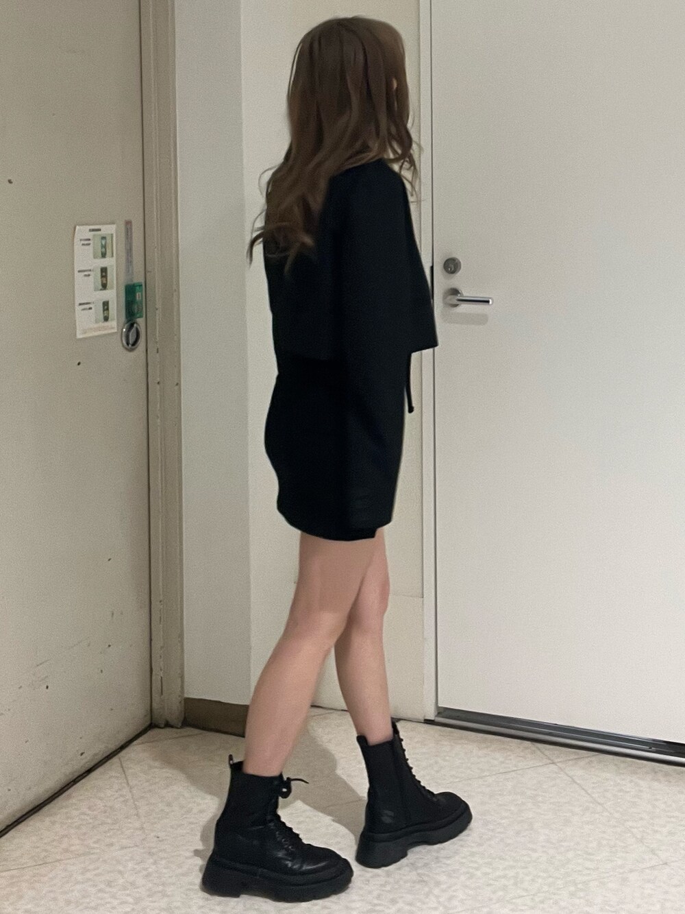 ブラック系のテーラードジャケット、ブラック系のワンピース、ブラック系のブーツを着用したレディースの春コーディネートの2枚目の写真