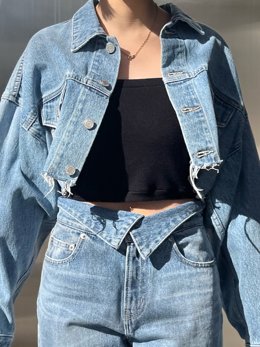 ブルー系のデニムジャケット、ブラック系のハンドバッグ、ブルー系のデニムパンツを着用したレディースの冬コーディネートの3枚目の写真