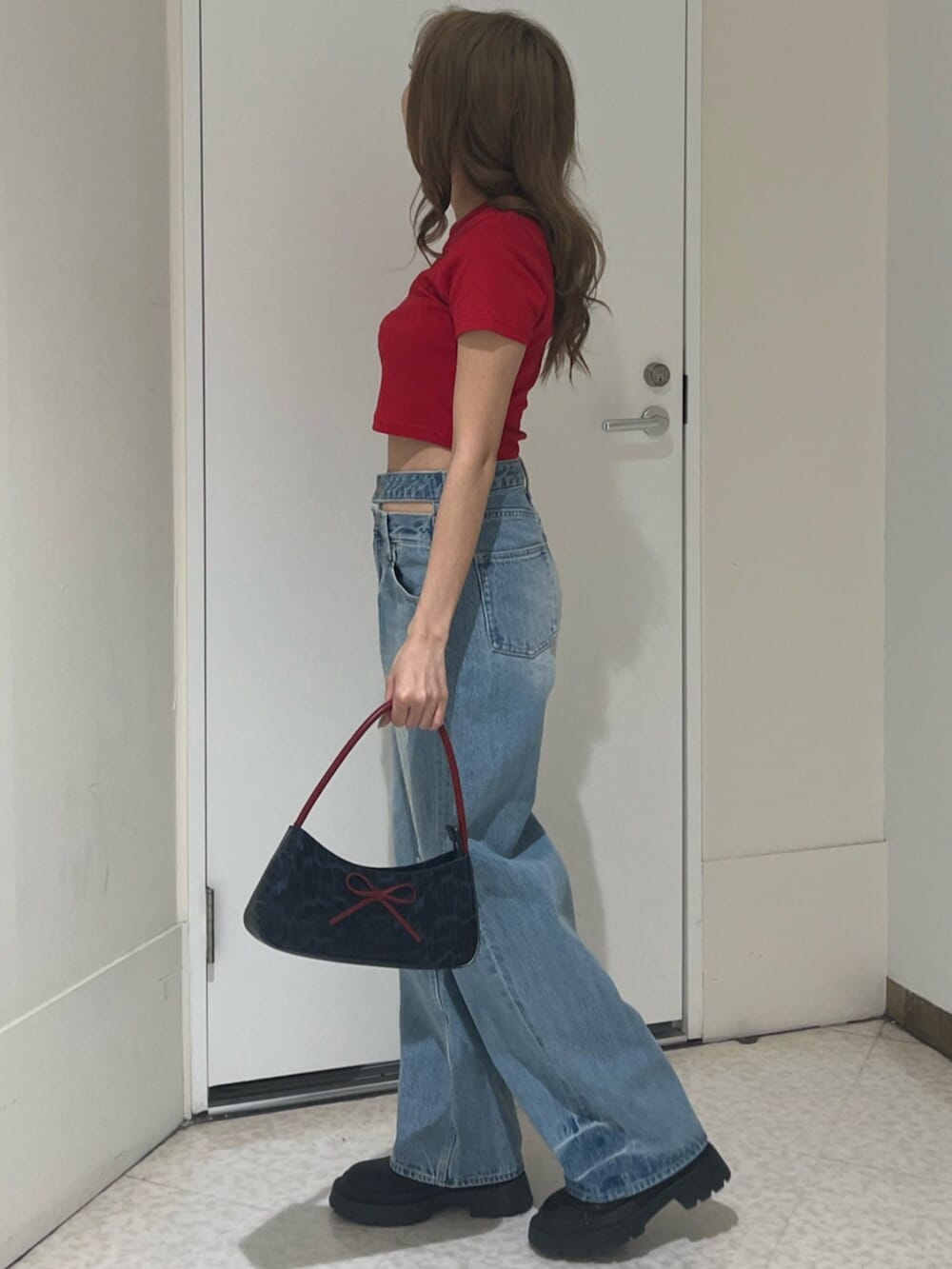 ブラック系のブーツ、ブラウン系のハンドバッグ、ブルー系のデニムパンツを着用したレディースの春コーディネートの3枚目の写真