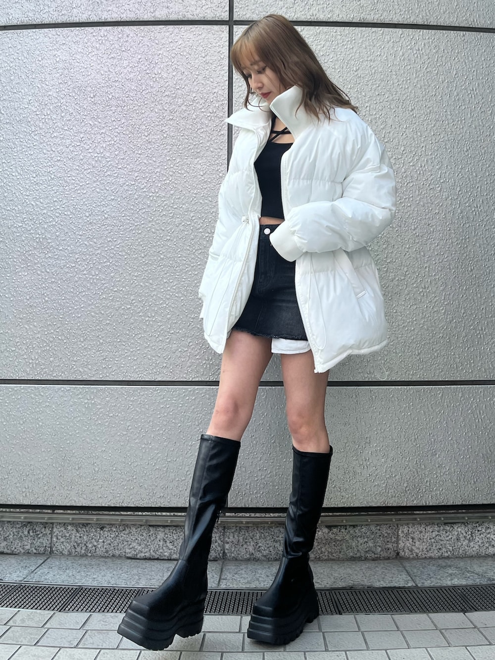 ブラック系のデニムスカート、ブラック系のTシャツ/カットソー、ブラック系のブーツを着用したレディースの冬コーディネートの2枚目の写真