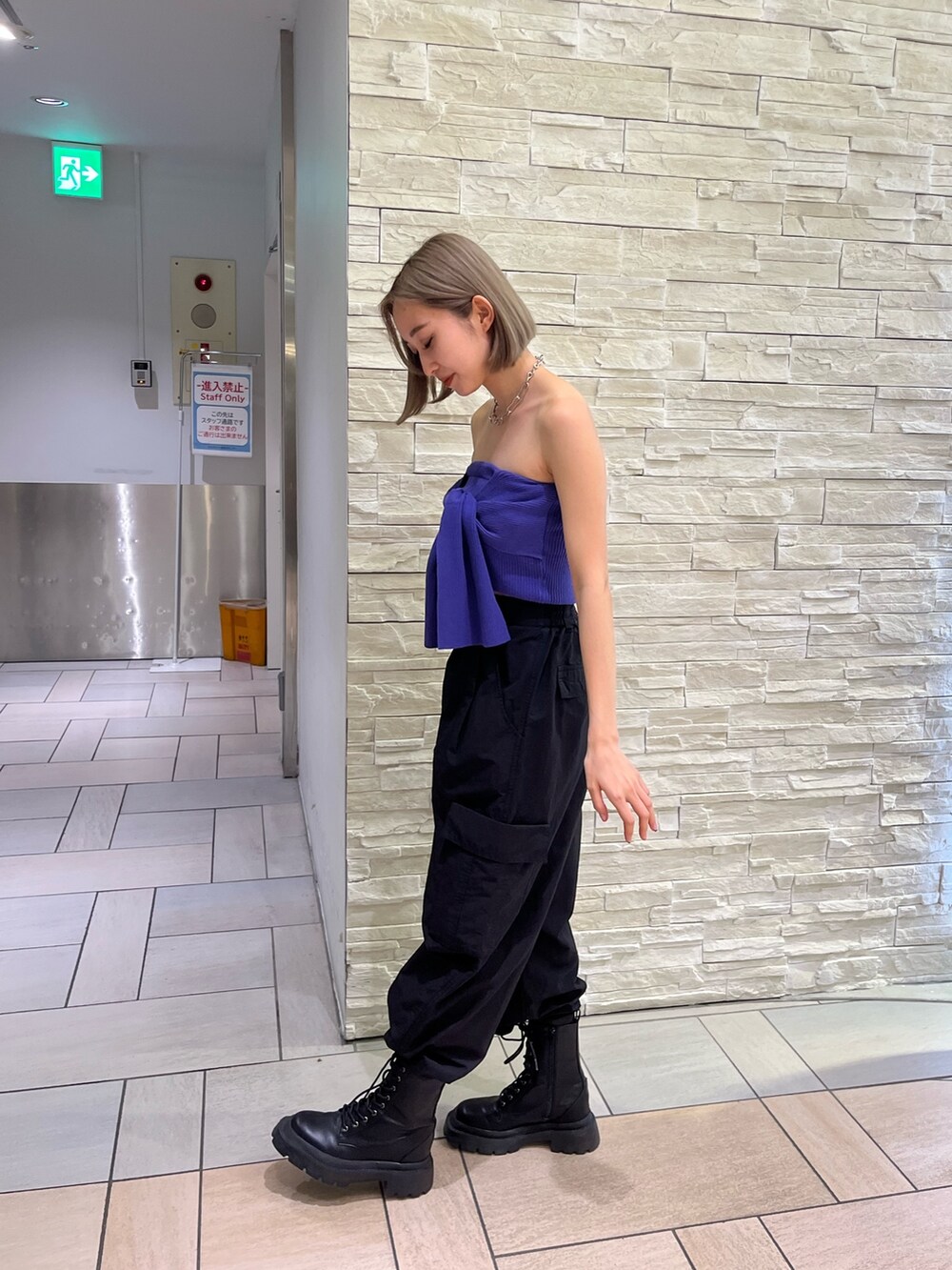 オレンジ系のカーゴパンツ、ブラック系のブーツ、パープル系のチューブトップを着用したレディースの春コーディネートの3枚目の写真