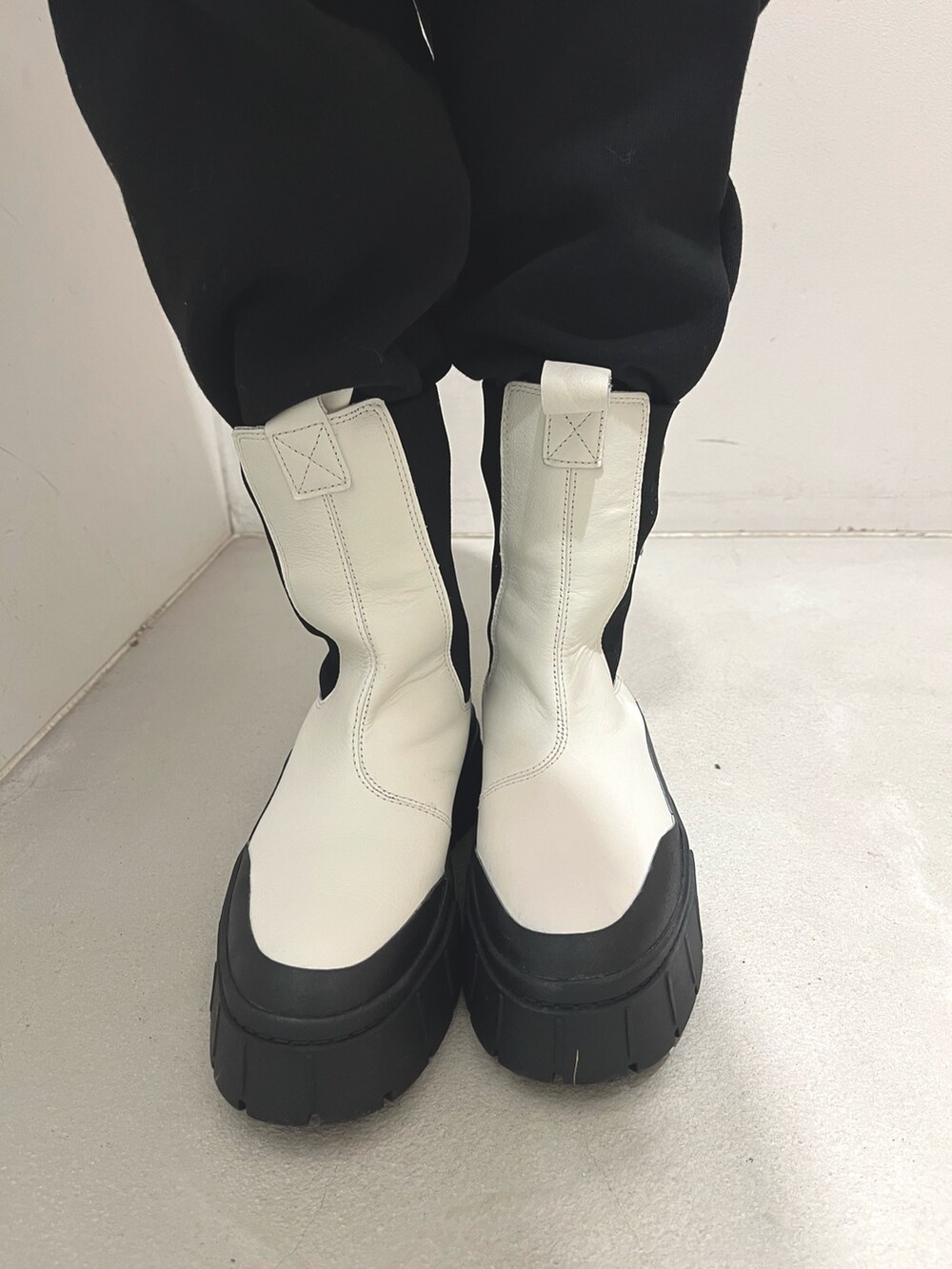 ブラック系のスウェットパンツ、ホワイト系のブーツ、ホワイト系のニット/セーターを着用したレディースの冬コーディネートの3枚目の写真