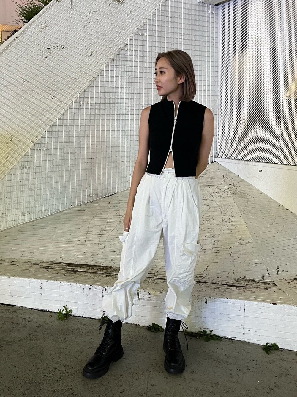 ホワイト系のカーゴパンツ、ブラック系のタンクトップ、ホワイト系のブーツを着用したレディースの夏コーディネートの2枚目の写真