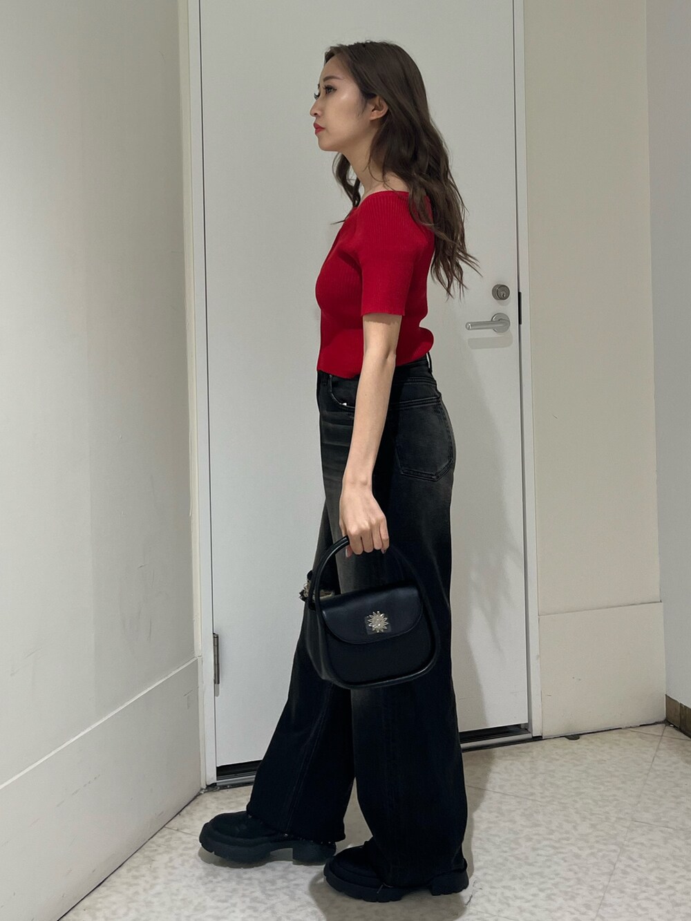 ブラック系のブーツ、ブラック系のデニムパンツ、ブラック系のハンドバッグを着用したレディースの春コーディネートの2枚目の写真