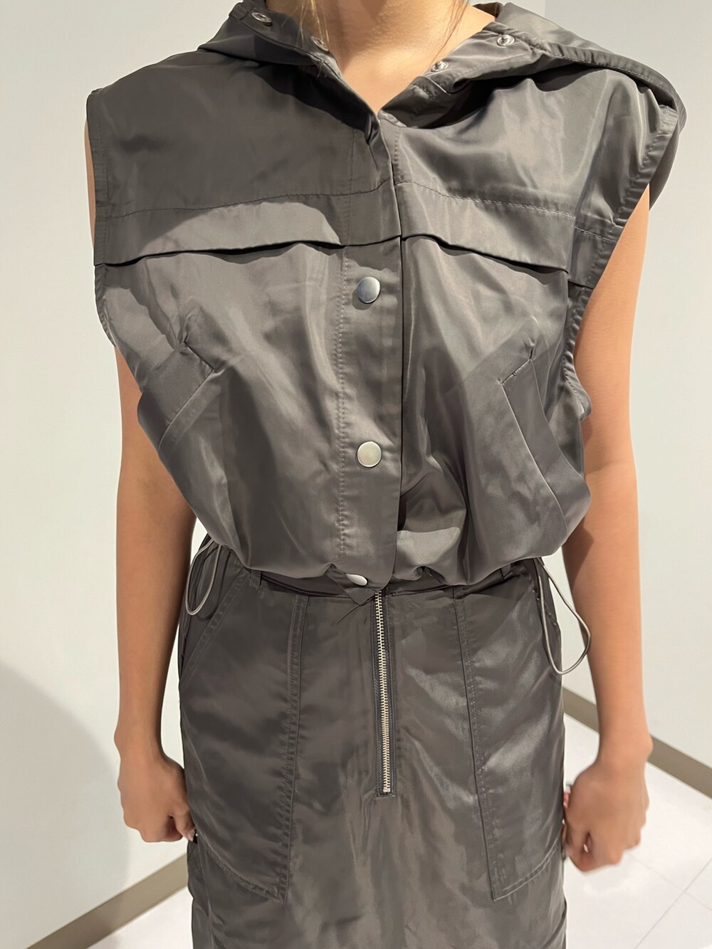 シルバー系のブーツ、グレー系のベスト、ホワイト系のスカートを着用したレディースの夏コーディネートの5枚目の写真