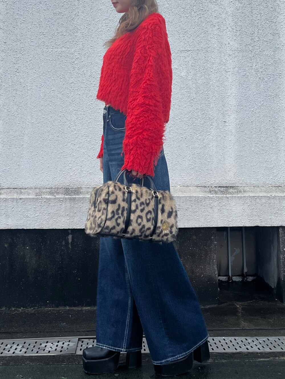 ブラック系のブーツ、レッド系のニット/セーター、ブルー系のデニムパンツを着用したレディースの冬コーディネートの2枚目の写真