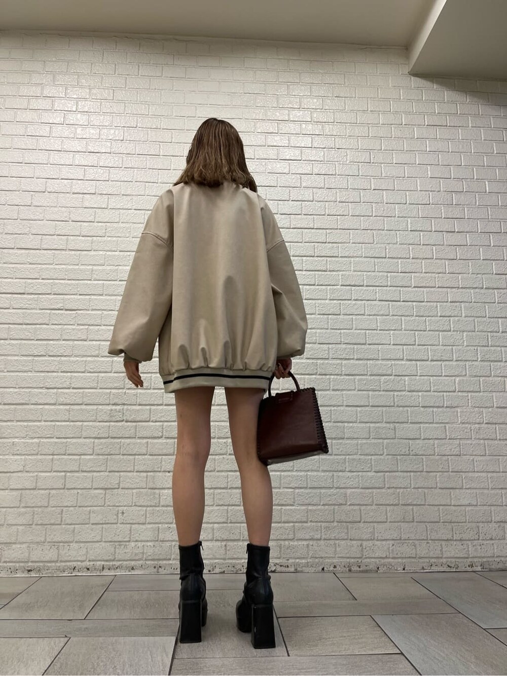 ブラック系のワンピース、ブラック系のブーツ、ベージュ系のブルゾンを着用したレディースの秋コーディネートの5枚目の写真