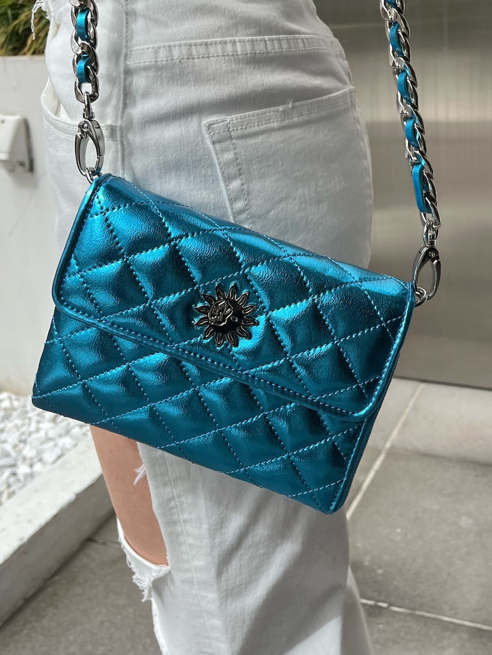 グリーン系のニット/セーター、ブラック系のデニムパンツ、ブラック系のショルダーバッグを着用したレディースの春コーディネートの7枚目の写真