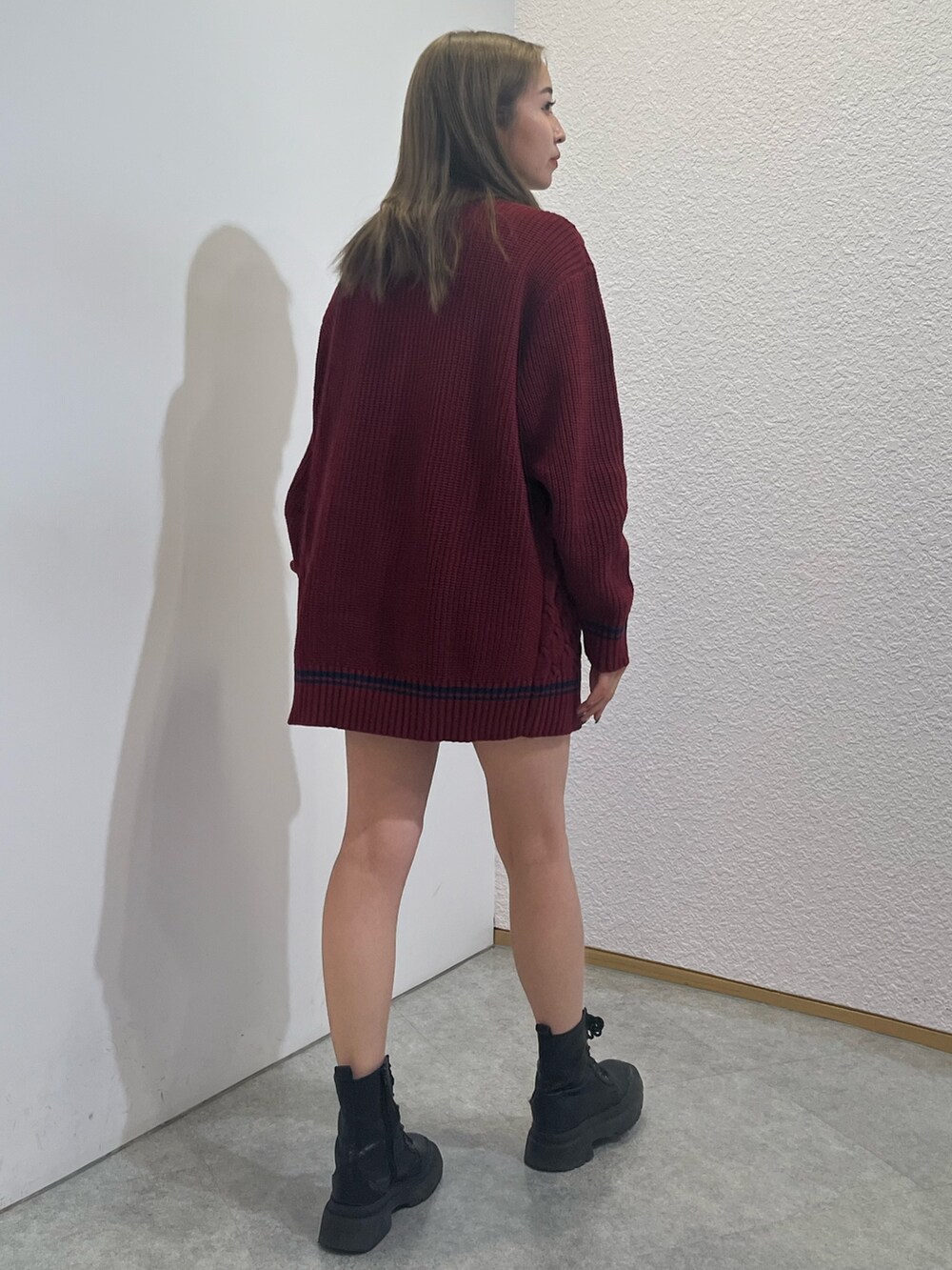 レッド系のニット/セーター、シルバー系のブーツ、ホワイト系のショルダーバッグを着用したレディースの夏コーディネートの3枚目の写真