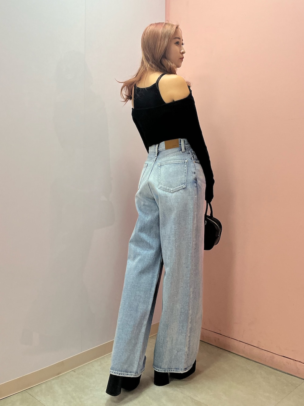 ブラック系のボストンバッグ、ブラック系のブーツ、イエロー系のニット/セーターを着用したレディースの春コーディネートの4枚目の写真