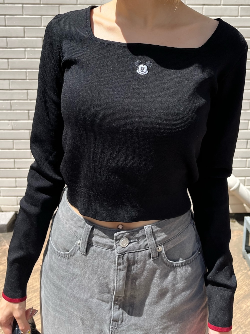 ブラック系のデニムスカート、ブラック系のブーツ、ブラック系のハンドバッグを着用したレディースの夏コーディネートの5枚目の写真