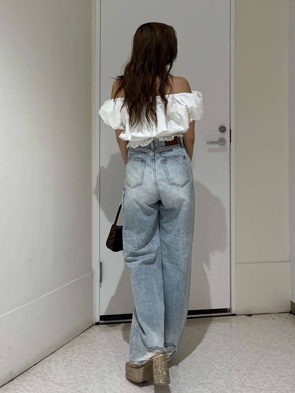 ホワイト系のシャツ/ブラウス、ブルー系のデニムパンツ、ブラウン系のハンドバッグを着用したレディースの夏コーディネートの3枚目の写真