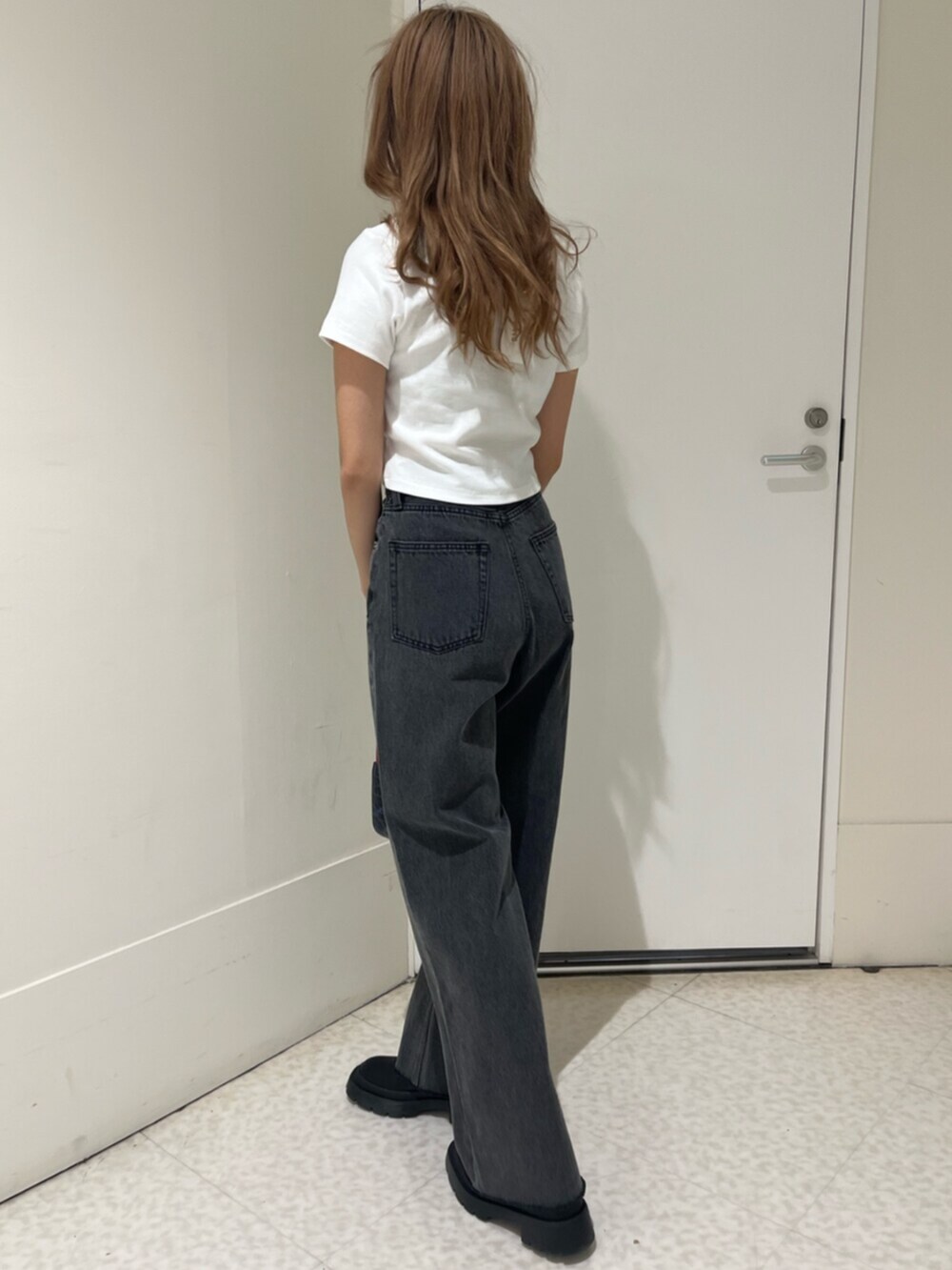 ブラック系のブーツ、ブラウン系のハンドバッグ、ブラック系のデニムパンツを着用したレディースの春コーディネートの3枚目の写真
