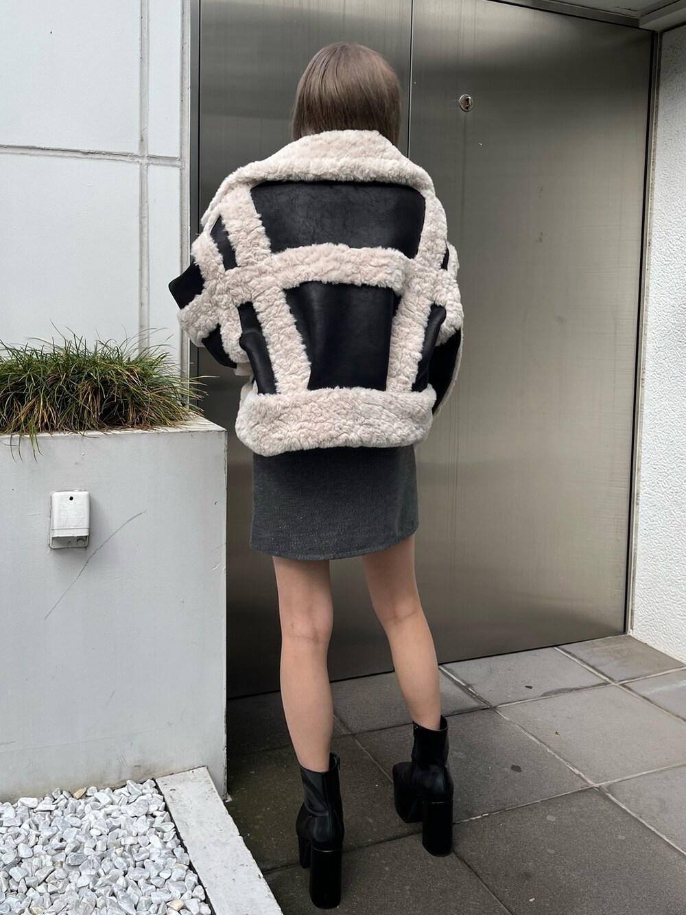 ブラック系のブーツ、ブラック系のショルダーバッグ、グリーン系のムートンコートを着用したレディースの冬コーディネートの6枚目の写真