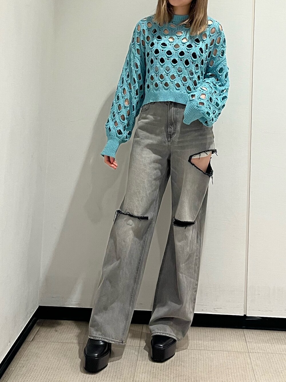 ブラック系のデニムパンツ、ブラック系のブーツ、ブルー系のニット/セーターを着用したレディースの冬コーディネートの2枚目の写真