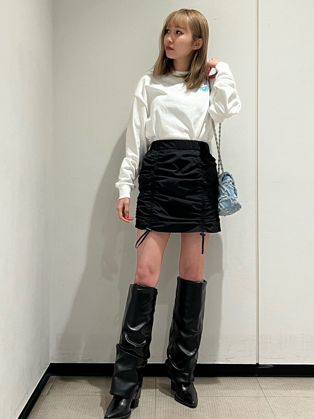 ホワイト系のブーツ、ブルー系のショルダーバッグ、ホワイト系のTシャツ/カットソーを着用したレディースの冬コーディネートの4枚目の写真