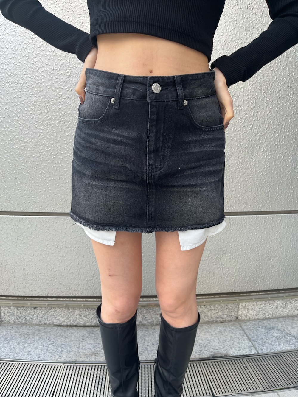 ブラック系のブーツ、ブラック系のTシャツ/カットソー、ブラック系のデニムスカートを着用したレディースの冬コーディネートの5枚目の写真