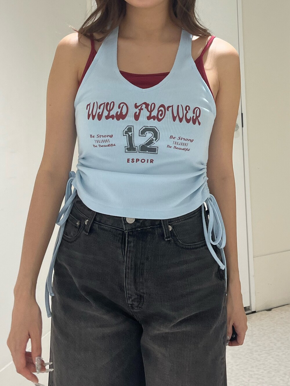 ブルー系のタンクトップ、ブラック系のデニムパンツ、ブラック系のブーツを着用したレディースの夏コーディネートの5枚目の写真