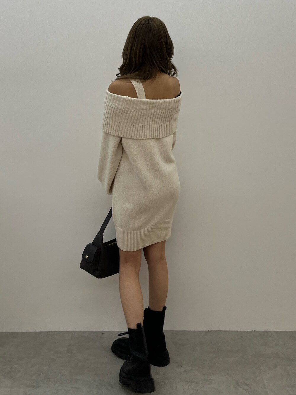 グレー系のハンドバッグ、ホワイト系のワンピース、ブラック系のブーツを着用したレディースの冬コーディネートの3枚目の写真