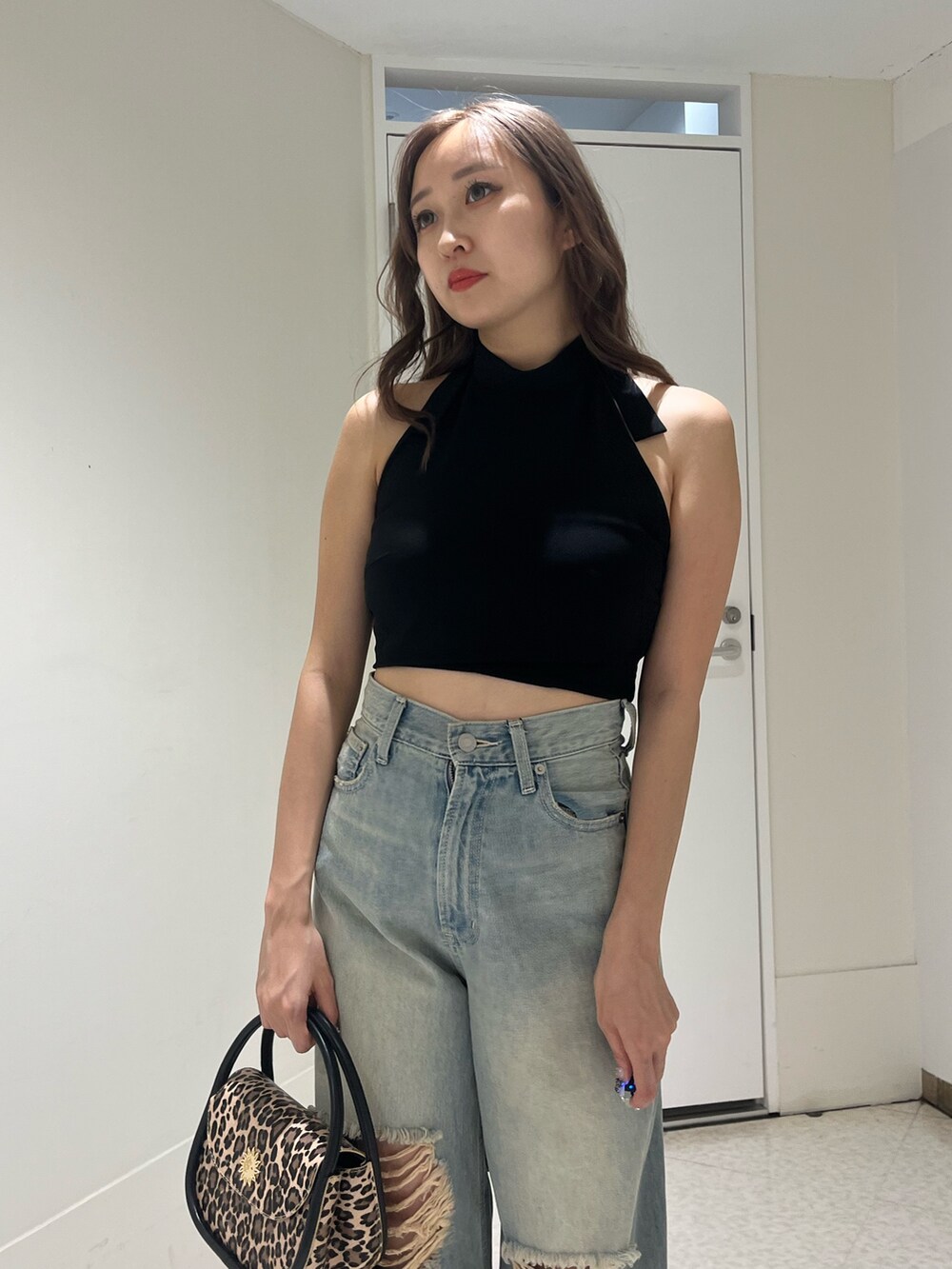 ブルー系のデニムパンツ、ブラック系のハンドバッグ、ブラック系のサンダルを着用したレディースの夏コーディネートの4枚目の写真