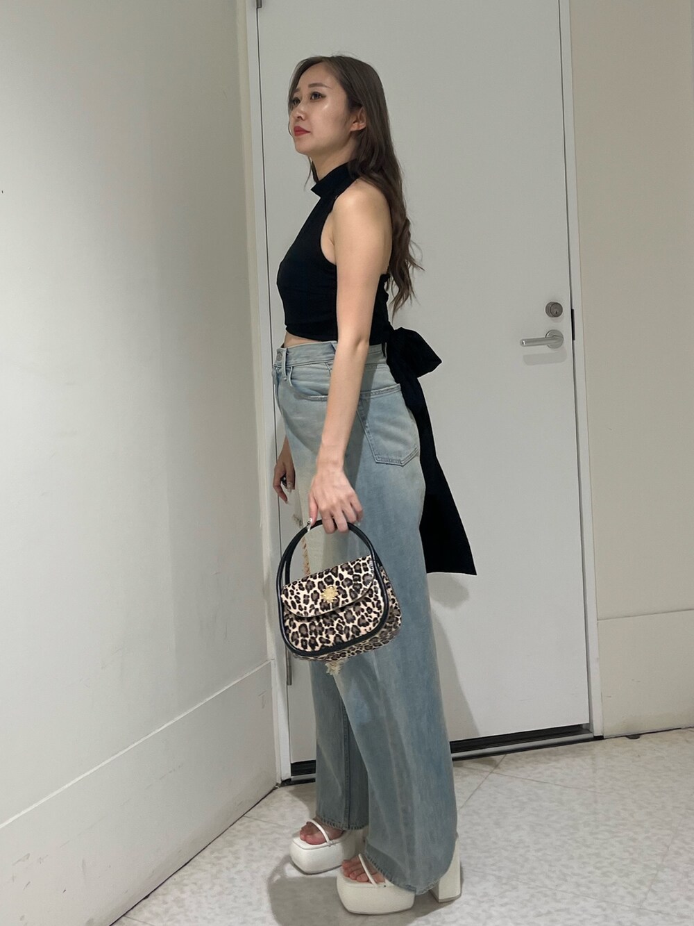 ブルー系のデニムパンツ、ブラック系のハンドバッグ、ブラック系のサンダルを着用したレディースの夏コーディネートの2枚目の写真