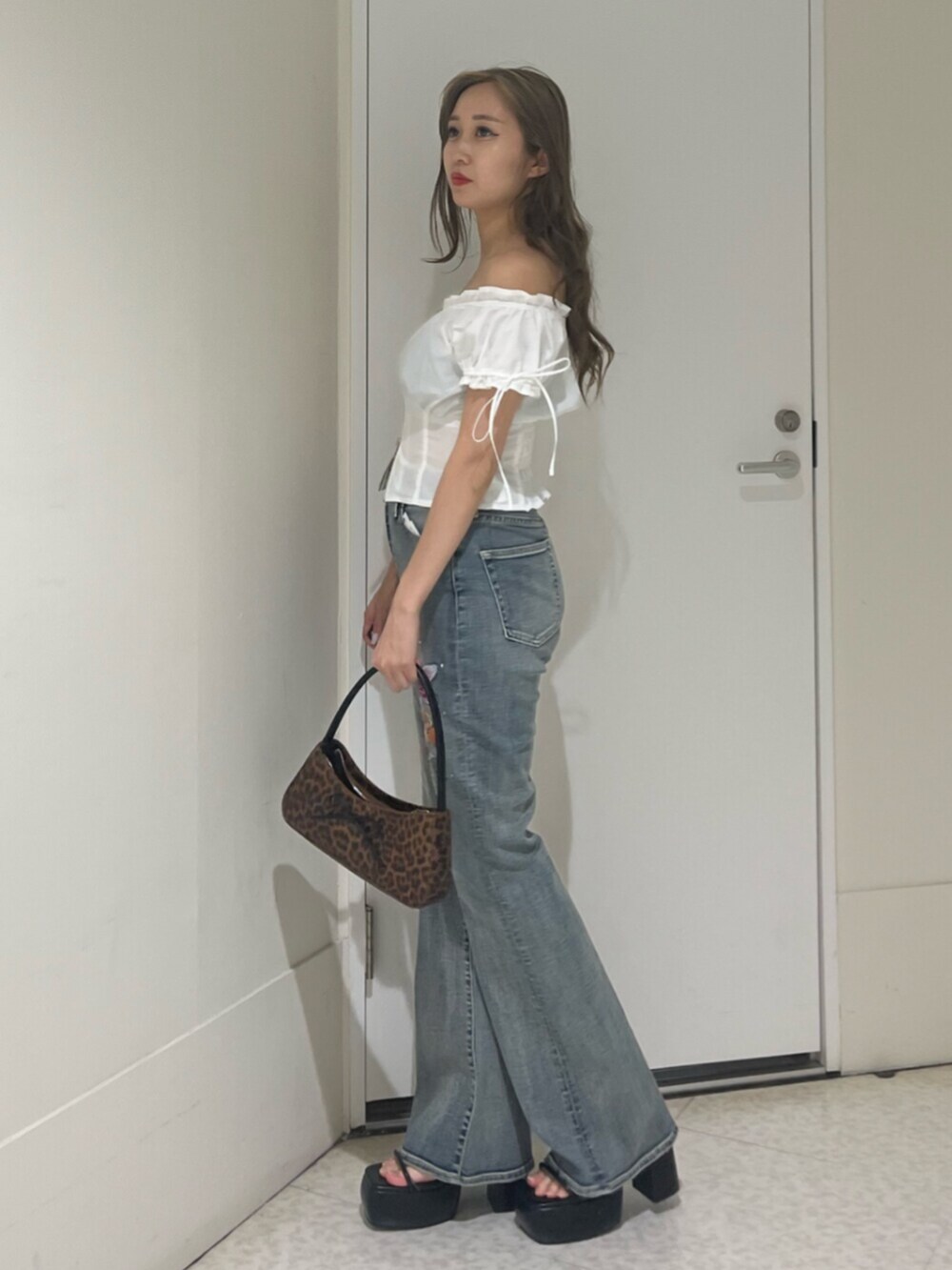 ブラウン系のハンドバッグ、ブラック系のサンダル、ホワイト系のシャツ/ブラウスを着用したレディースの夏コーディネートの2枚目の写真