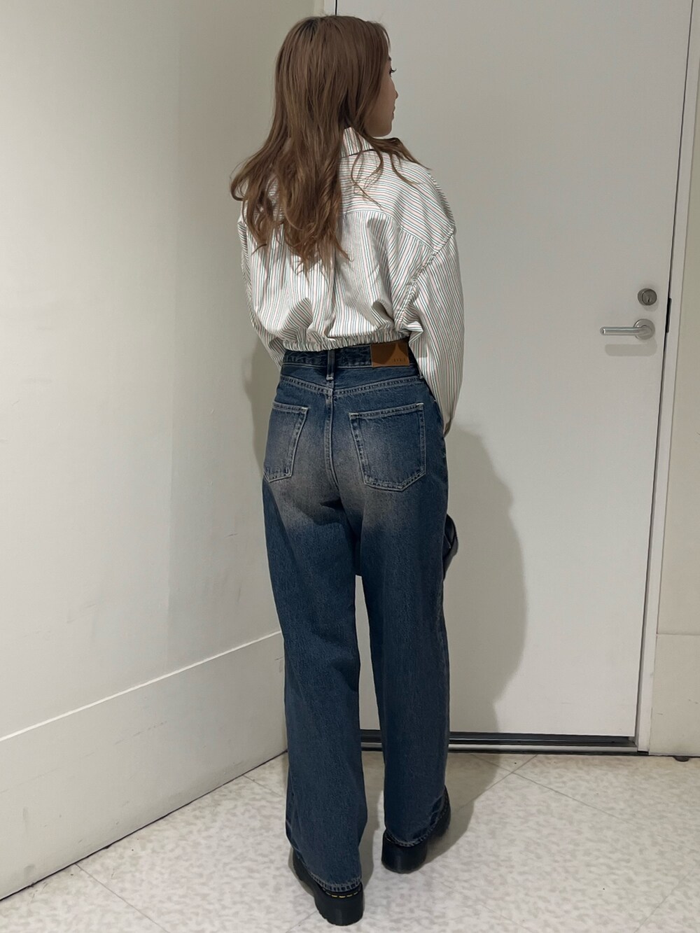 ブルー系のシャツ/ブラウス、ブルー系のデニムパンツ、ブラック系のブーツを着用したレディースの春コーディネートの4枚目の写真