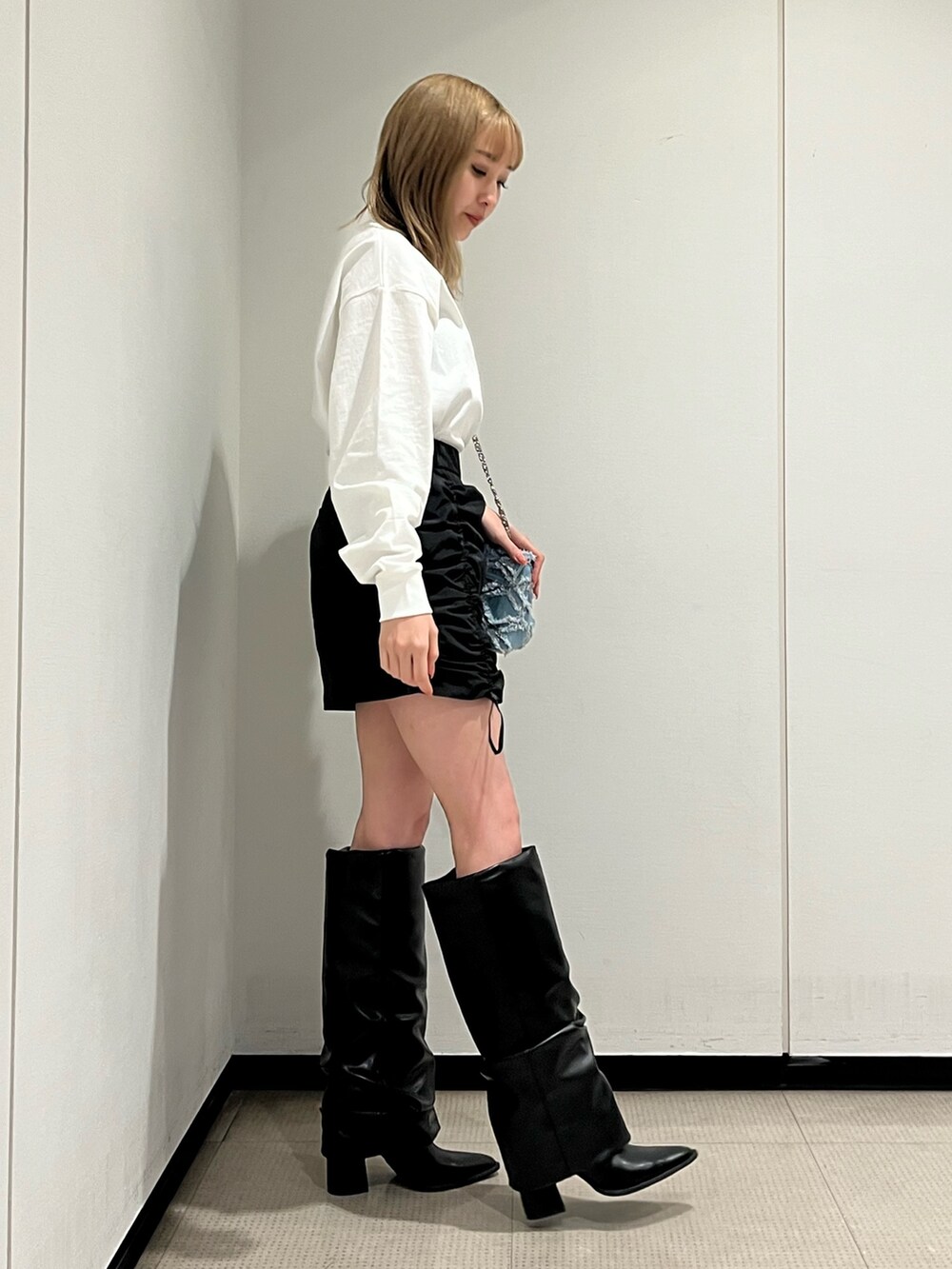 ホワイト系のブーツ、ブルー系のショルダーバッグ、ホワイト系のTシャツ/カットソーを着用したレディースの冬コーディネートの3枚目の写真
