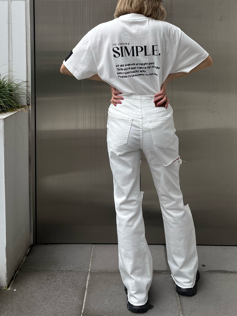 ホワイト系のデニムパンツ、ホワイト系のTシャツ/カットソー、ブラック系のスニーカーを着用したレディースの春コーディネートの3枚目の写真