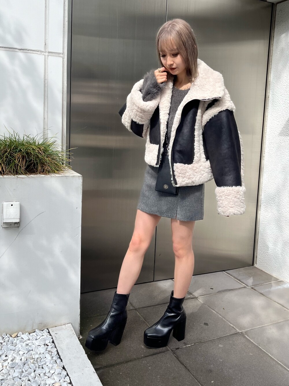 ブラック系のブーツ、ブラック系のショルダーバッグ、グリーン系のムートンコートを着用したレディースの冬コーディネートの2枚目の写真