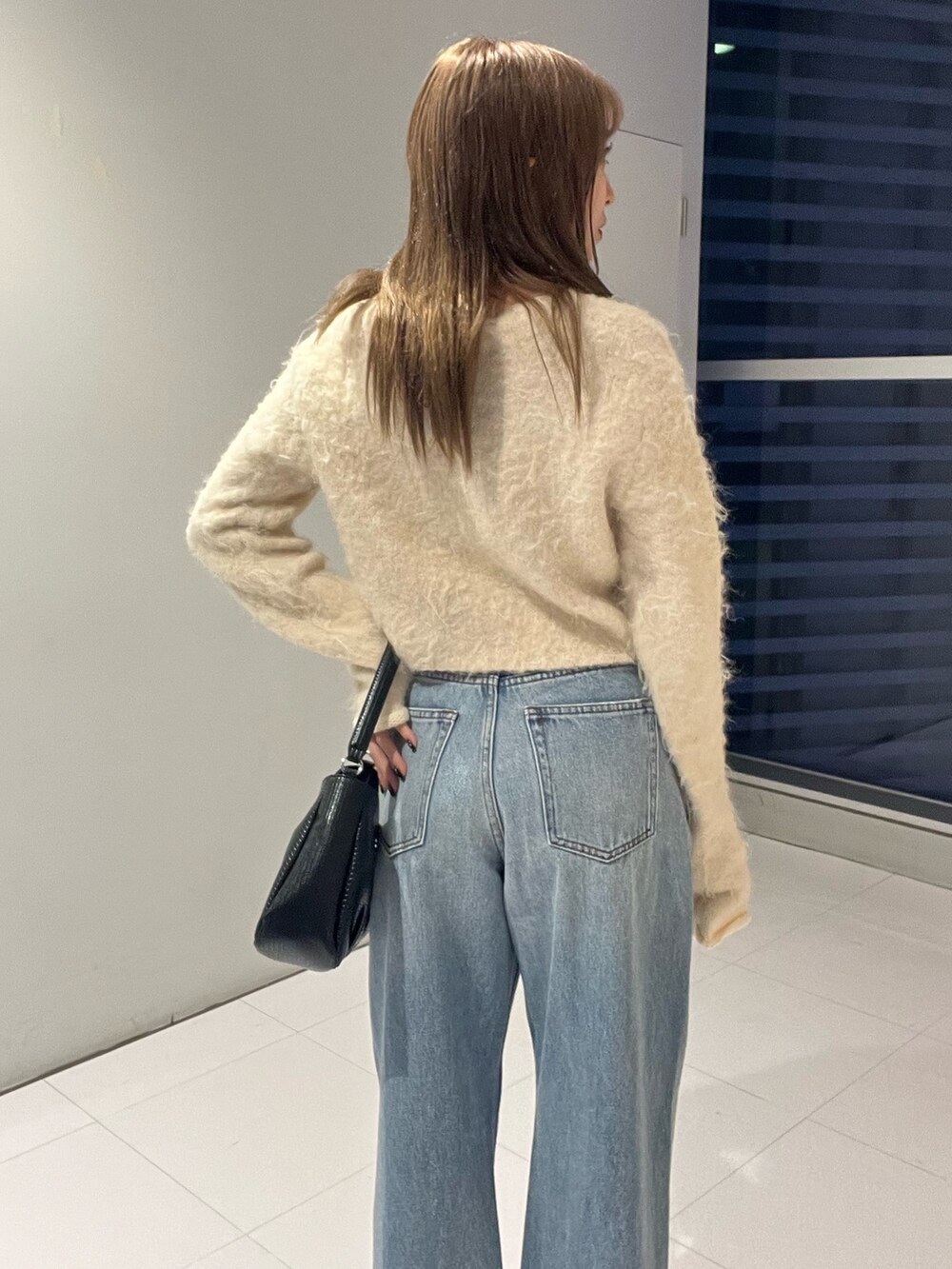 ブルー系のデニムパンツ、ブラック系のハンドバッグ、ホワイト系のニット/セーターを着用したレディースの秋コーディネートの7枚目の写真