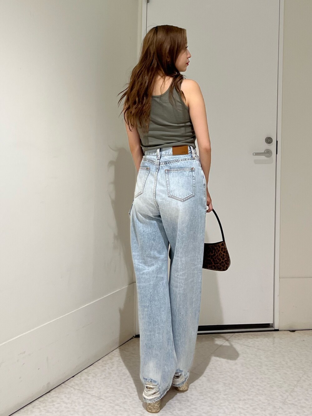 ブラウン系のハンドバッグ、シルバー系のサンダル、ブルー系のデニムパンツを着用したレディースの夏コーディネートの2枚目の写真