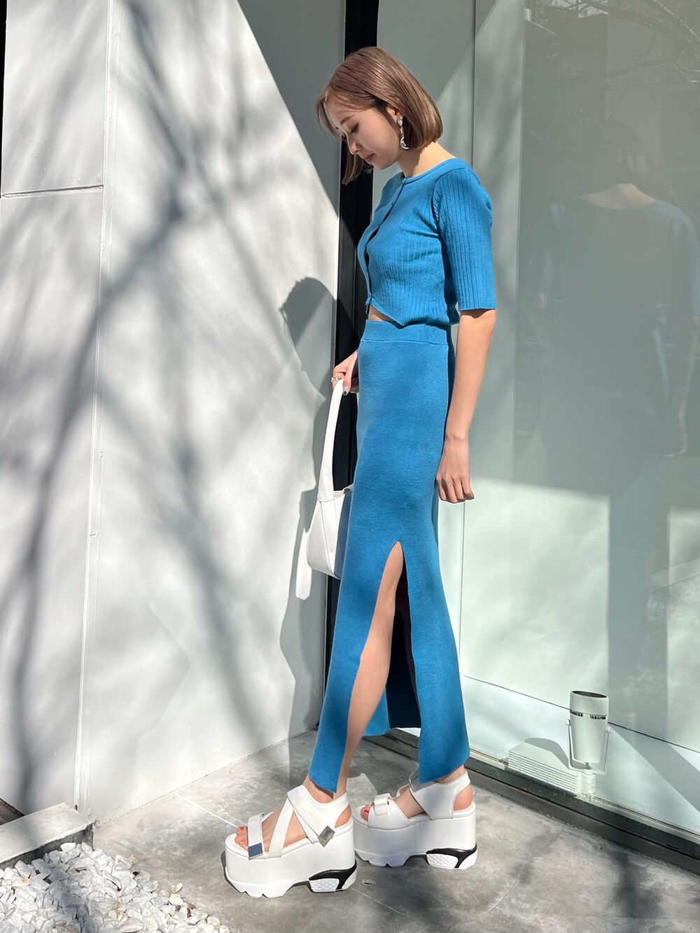 ブルー系のワンピース、ブラック系のハンドバッグを着用したレディースの春コーディネートの2枚目の写真