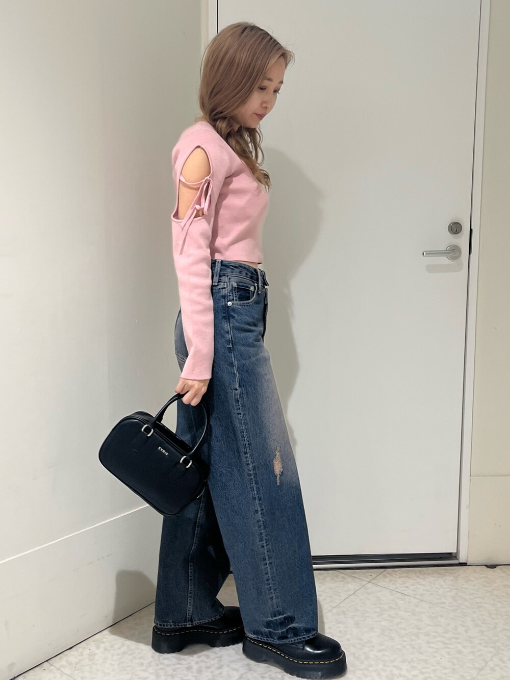 ブルー系のデニムパンツ、ピンク系のニット/セーター、ブラック系のボストンバッグを着用したレディースの春コーディネートの4枚目の写真