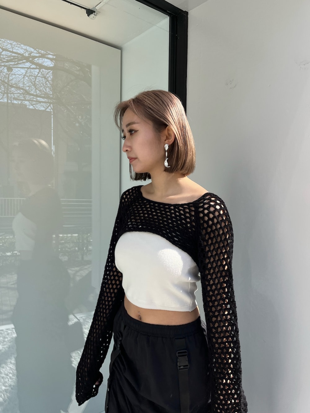 ブラック系のスカート、ブラック系のニット/セーター、パープル系のハンドバッグを着用したレディースの春コーディネートの3枚目の写真